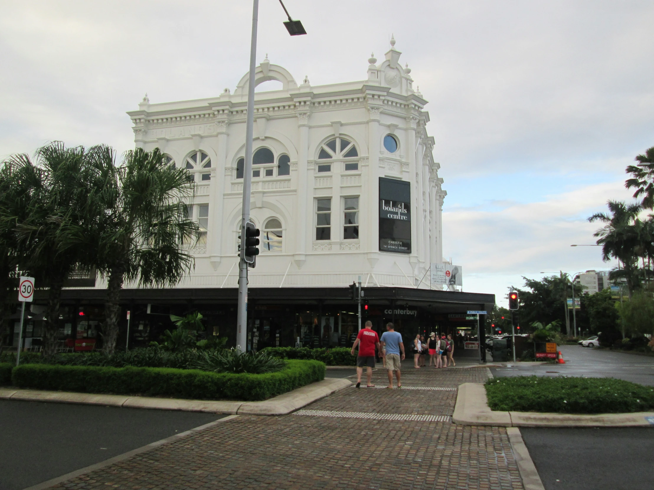 a white building with arched windows and many people walking by it