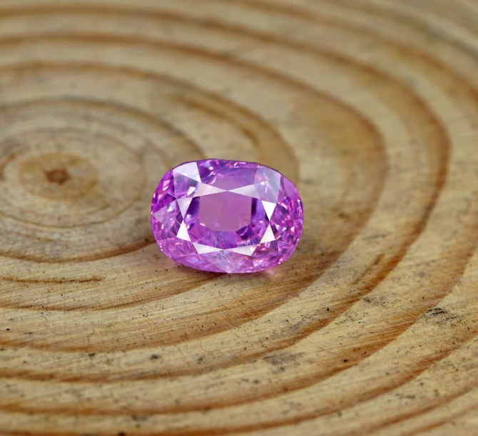 a purple ayst gemstone sitting on top of a wooden background
