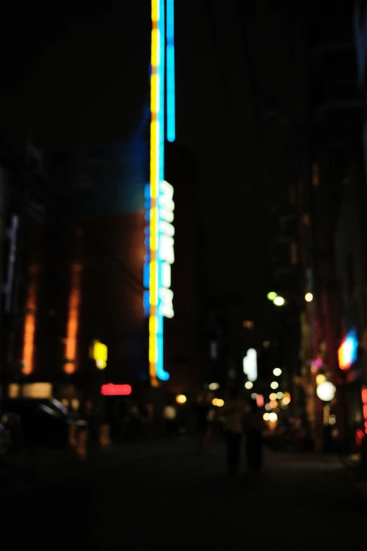 a city street with a tall building lit up at night