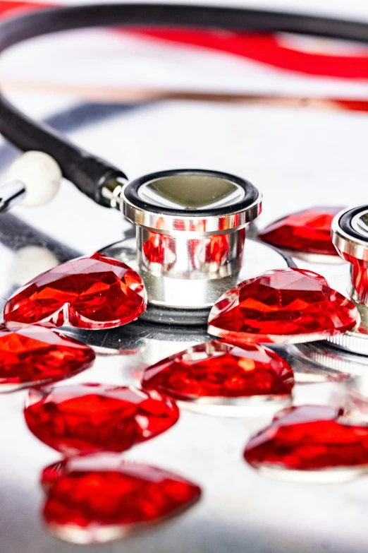 several heart charms lay on top of a stethoscope