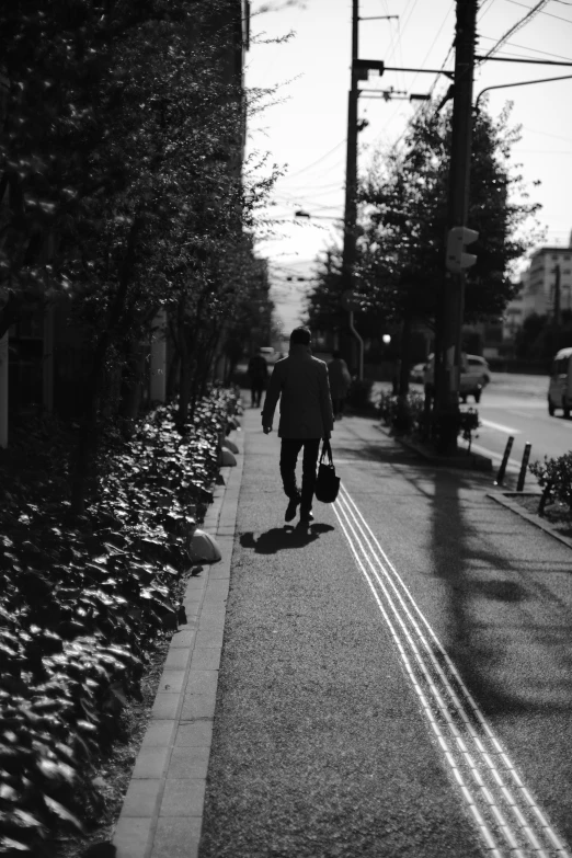 a man walking down the road holding an umbrella