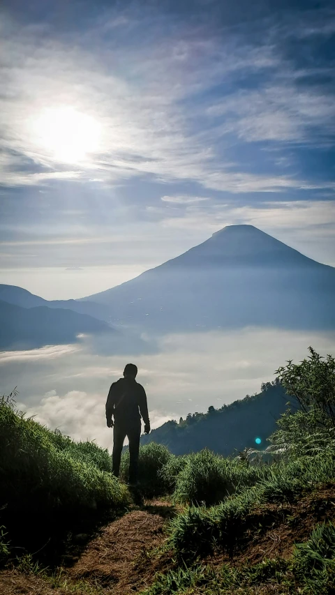 a man stands on a mountain top overlooking the clouds