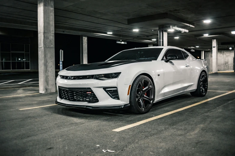 a chevrolet camaro on some black wheels in a parking lot