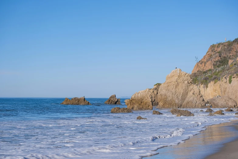 a couple walking along the beach with a surfboard