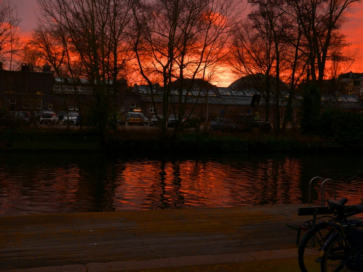 a bicycle next to a body of water at sunset