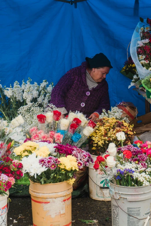 woman sitting with lots of flowers in buckets