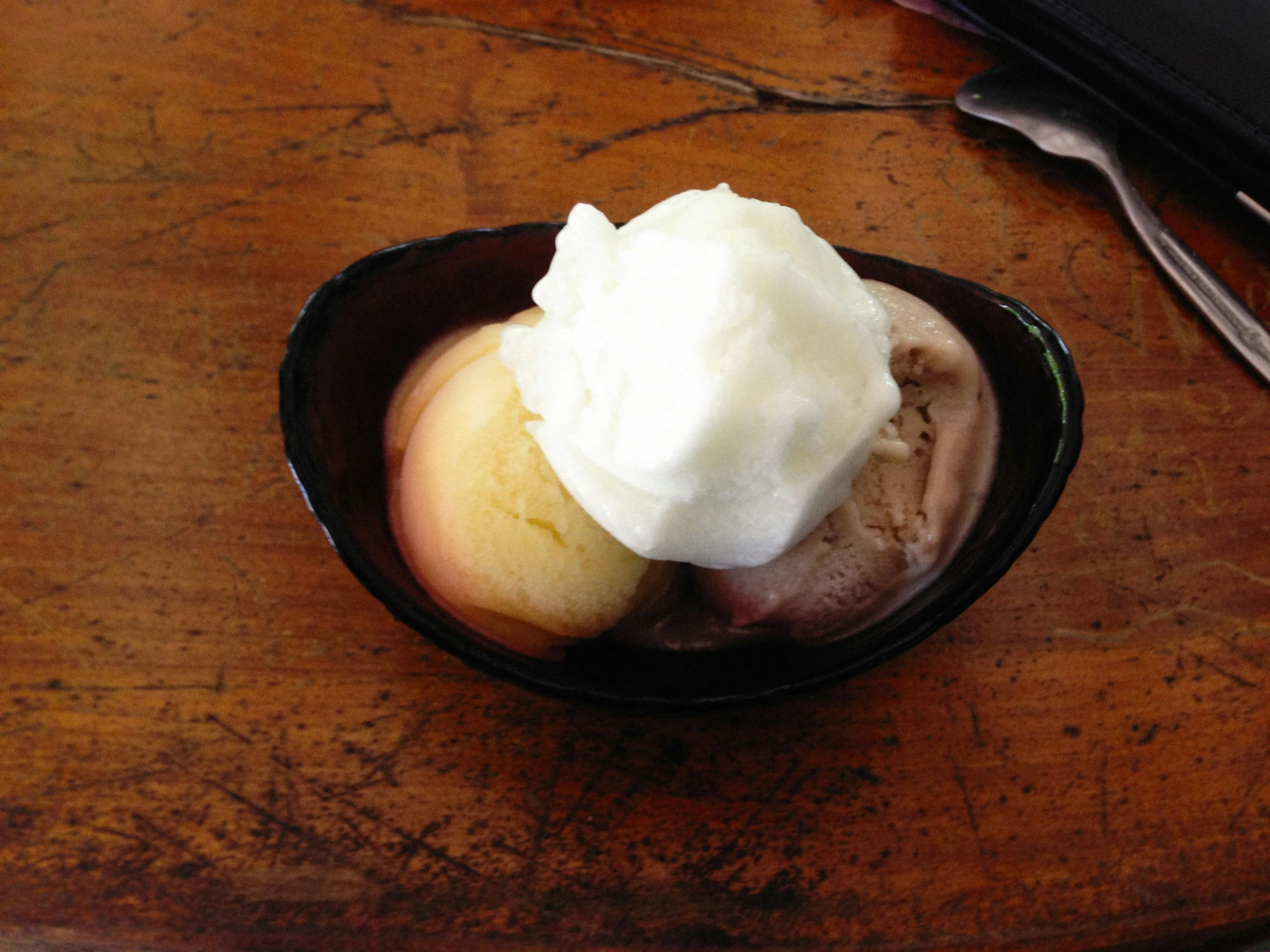 a wooden table topped with a bowl filled with ice cream and a fruit slice