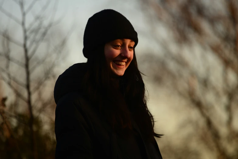 a smiling girl in a coat holding her cell phone