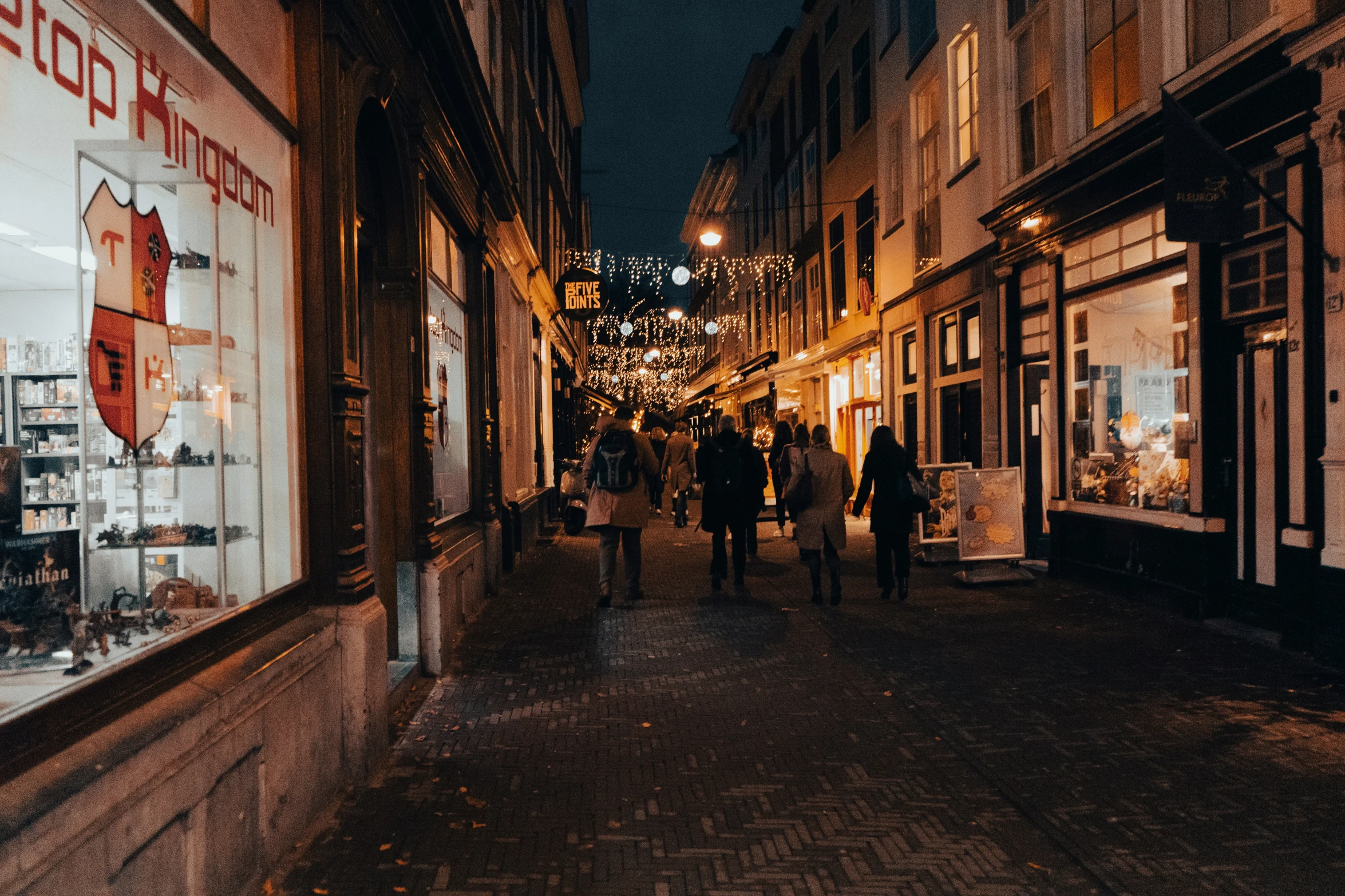 pedestrians walk along a narrow street in the evening
