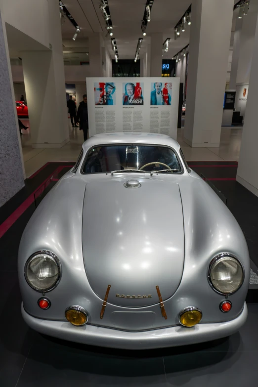 an old white sports car on display in a museum