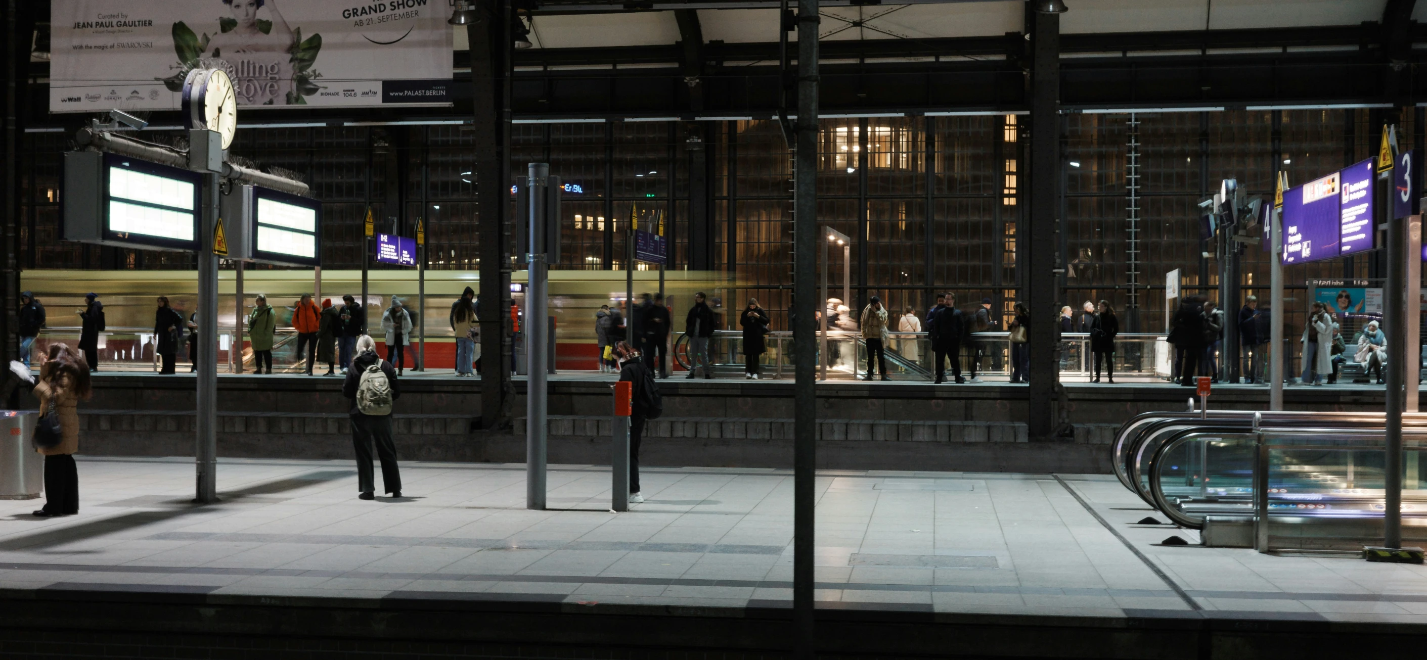 people walking by the window of a building at night