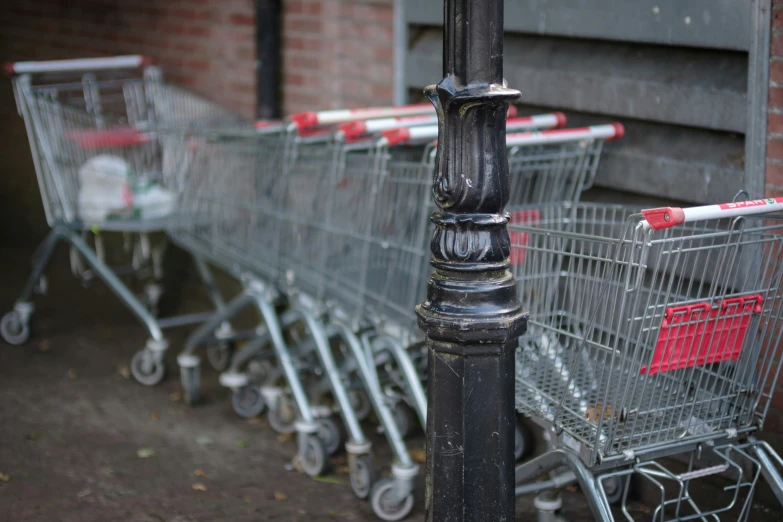 several shopping carts that are lined up against a pole