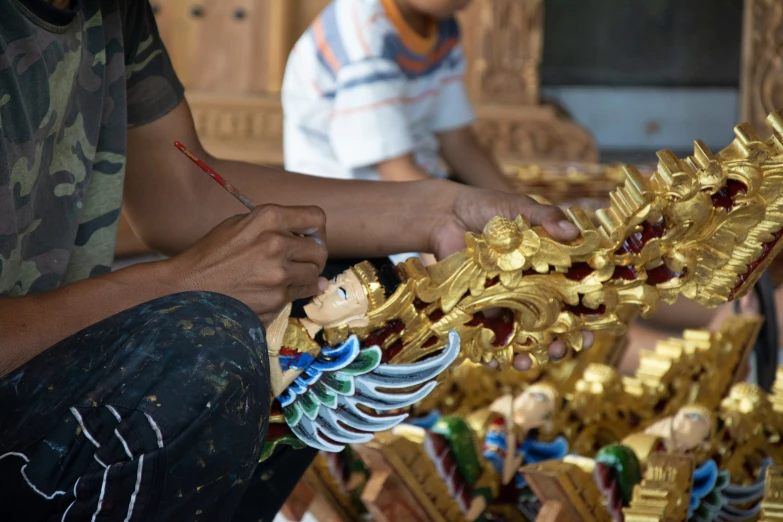 a pair of hands is working on gold statues