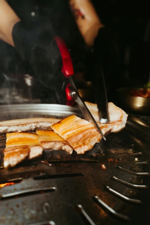 a person cuts food on top of a  grill