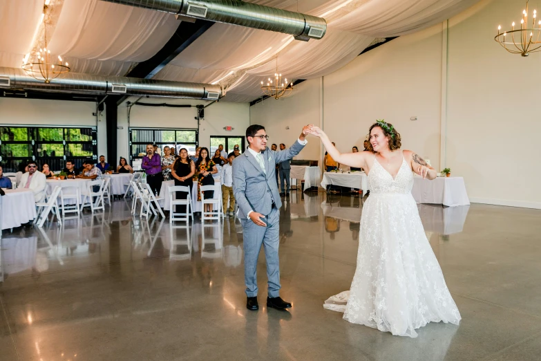 bride and grooms are dancing in the center of a room full of guests