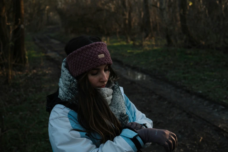 girl in white jacket and dark cap looking down at the ground