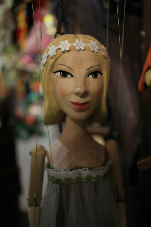 a doll wearing a dress holding a string and wearing a flower headband