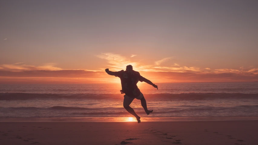 a man standing on top of a sandy beach next to the ocean