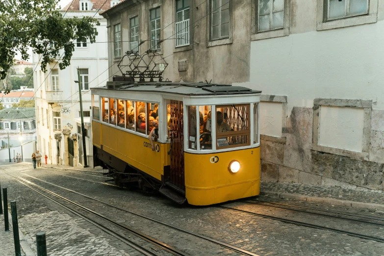 a trolley going through an old town with cars and a light rail