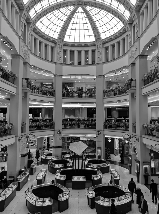 black and white pograph of people in shopping mall looking at laptops