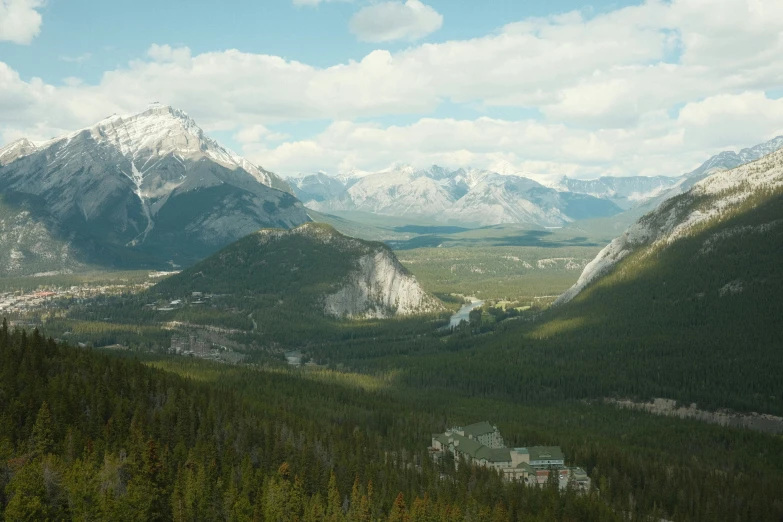 a forested valley with mountains on the horizon