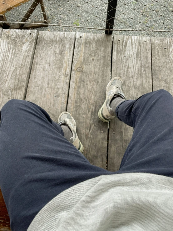 person wearing jeans with gray shoes on the ground