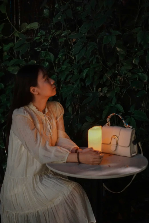 a young woman is holding a candle on a small table