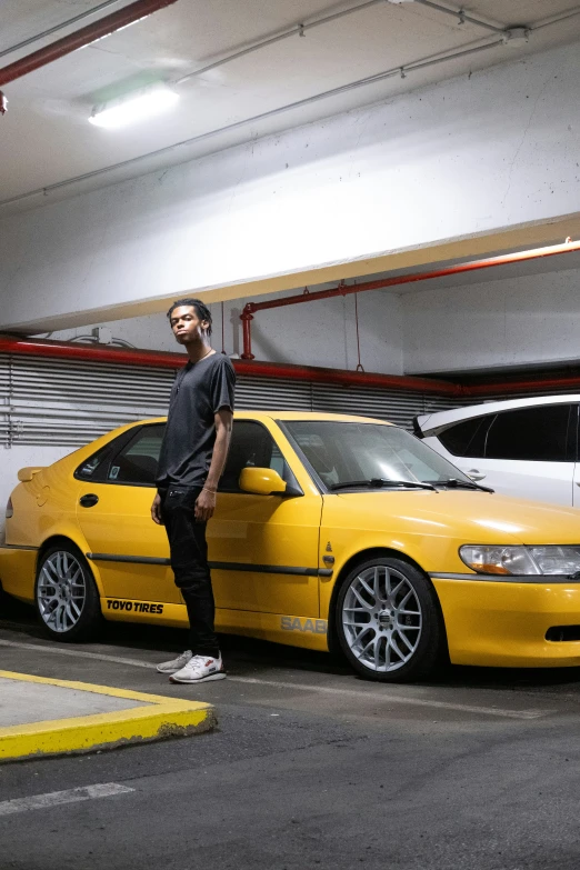 a man leaning against a yellow car parked in the garage