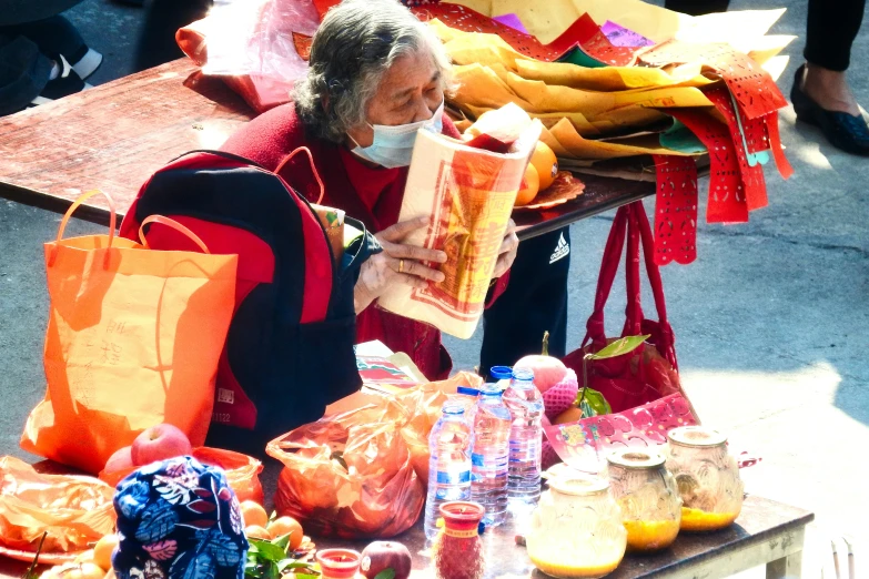 a woman is sitting in front of a table selling fruits
