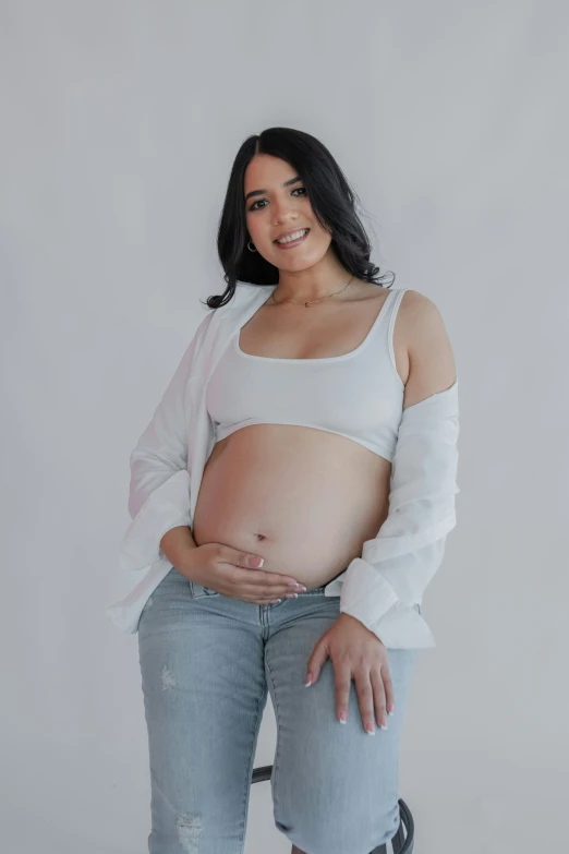 an adult in jeans standing with her belly exposed