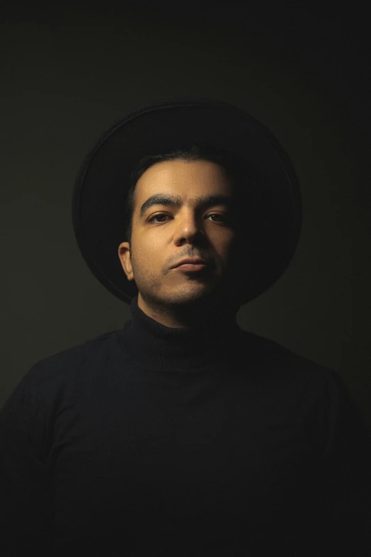 a man in black shirt and hat staring at the camera