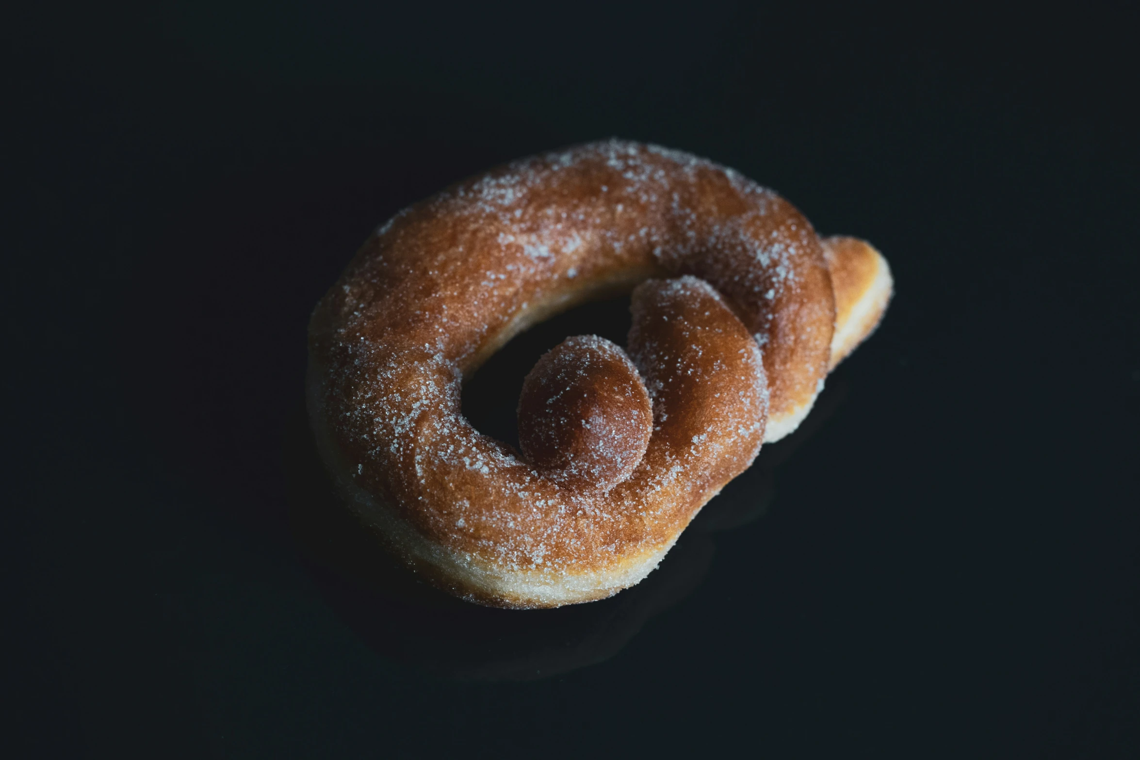 three sugared donuts sitting on top of a black surface