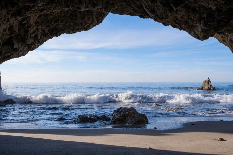 a beach area with several rocks and an ocean wave