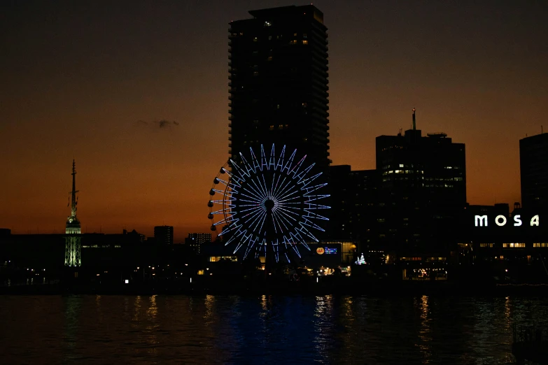 a ferris wheel sitting on top of a river next to a tall building