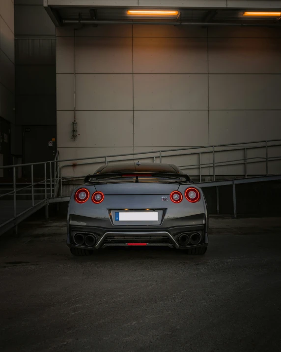 the back end of a silver sports car with chrome accents