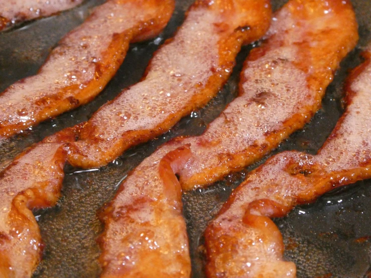 cooked bacon strips cooking in a pan on a counter