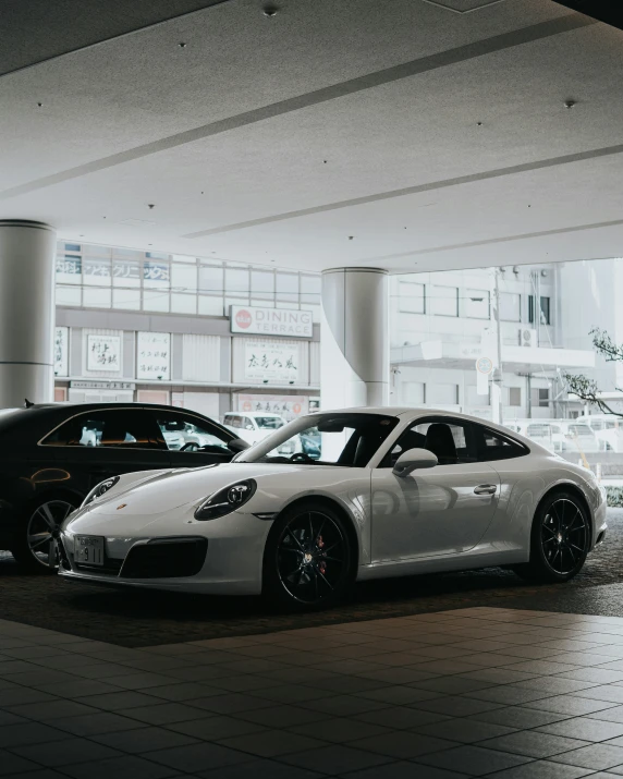 two porsche sports cars are parked in a big room