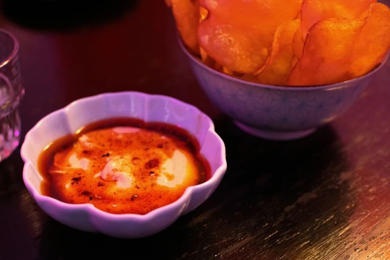 a bowl of soup, basket of fries and wine bottle on the side