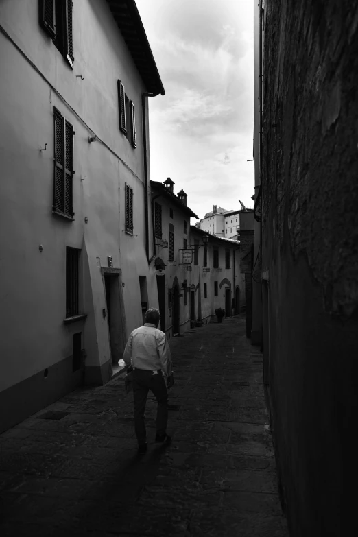 a man in a white coat walks down an alleyway