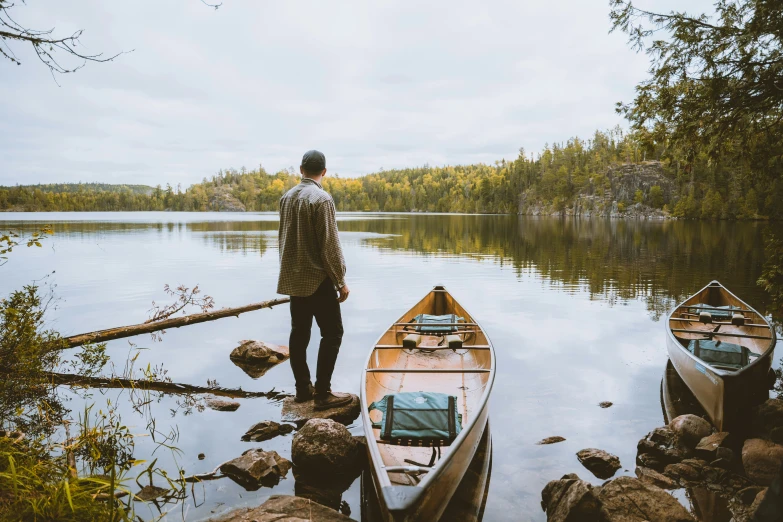 a man is standing by some boats on the shore