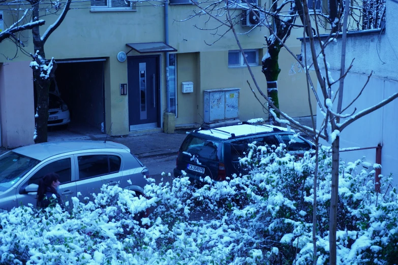 this snow covered neighborhood includes cars and parking spots