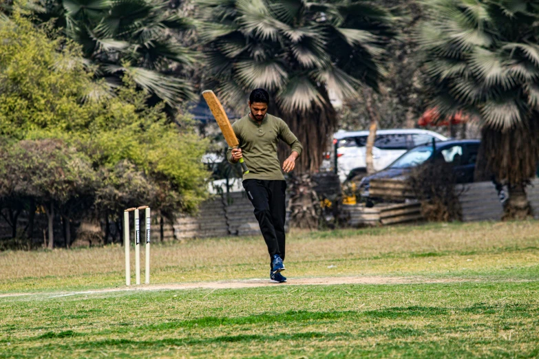 a person holding a bat walking toward a ball