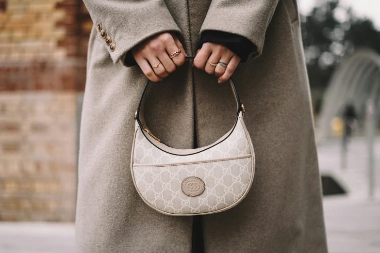 a woman is holding a beige handbag while she holds it up