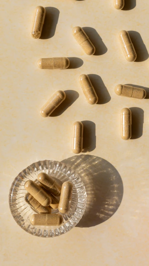 a plate topped with lots of pills next to a bowl of pill caps