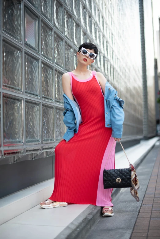 a woman wearing a red and pink dress, jacket, bag, and white sunglasses