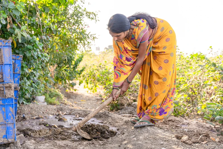 two women in yellow clothing work on a small hole