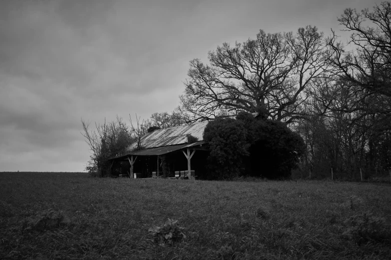 an old barn is in the middle of a field