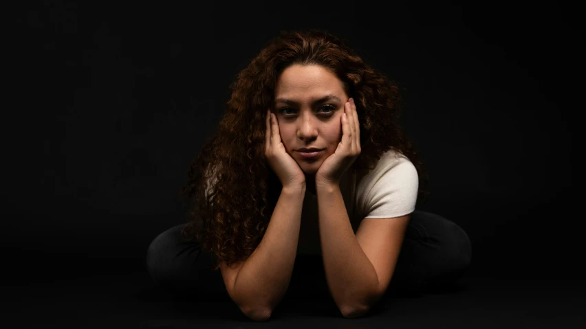 woman with curly hair sitting down on her stomach