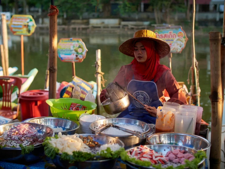 woman in vietnamese hat cooking food at table