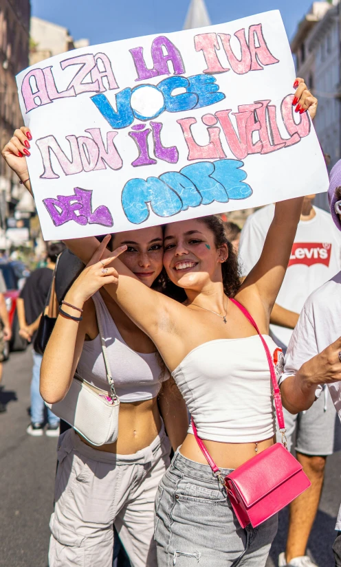 two women standing next to each other holding up a sign